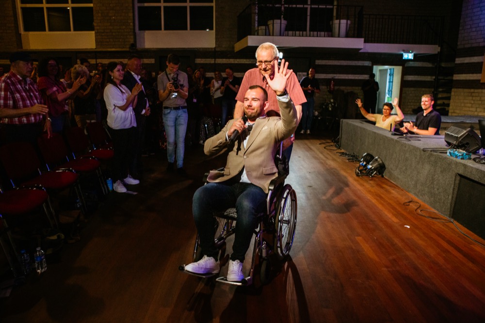 Bezoeker in rolstoel zwaait na gebed
