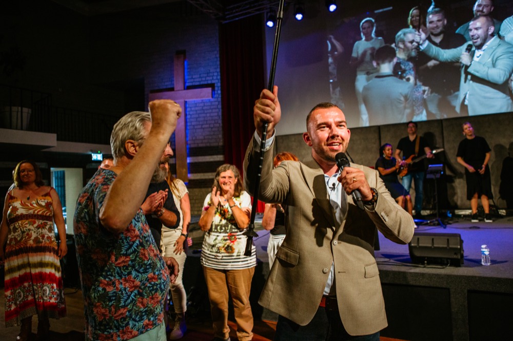 Bezoeker steekt zijn stok omhoog terwijl de zaal juicht