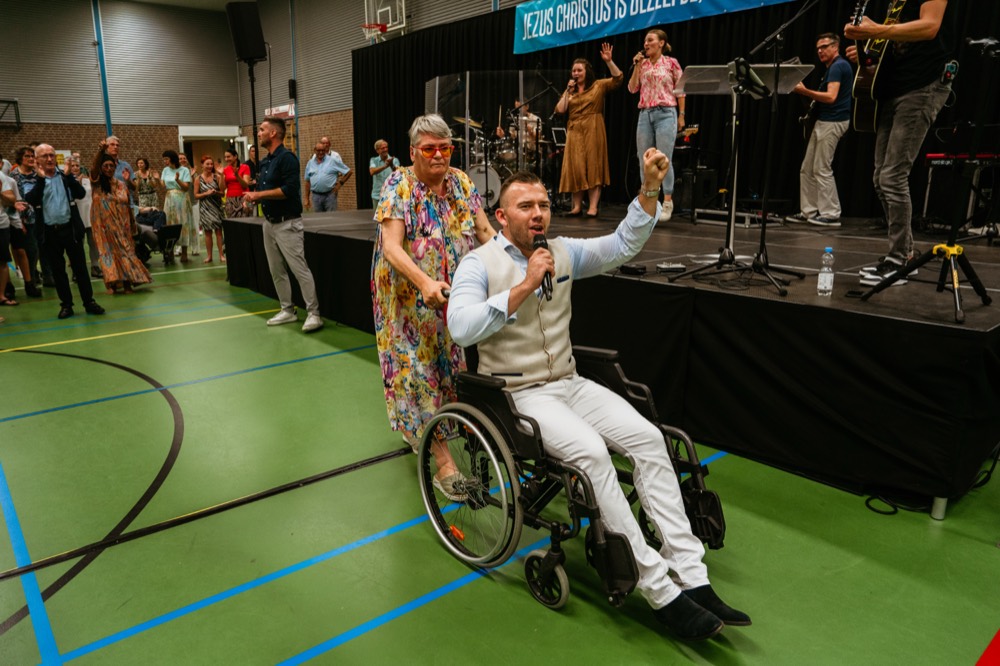 Bezoeker staat op en steekt zijn arm omhoog na gebed